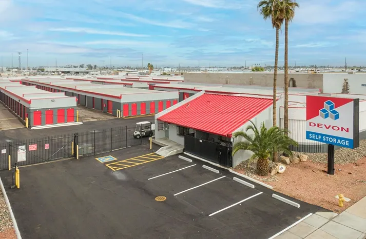 Storage facility entrance with office building, gated access, and parking area